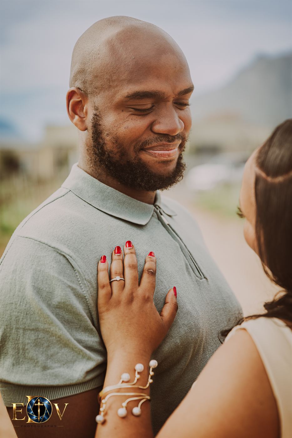Close view of a woman's hand and engagement ring resting on her partner's chest
