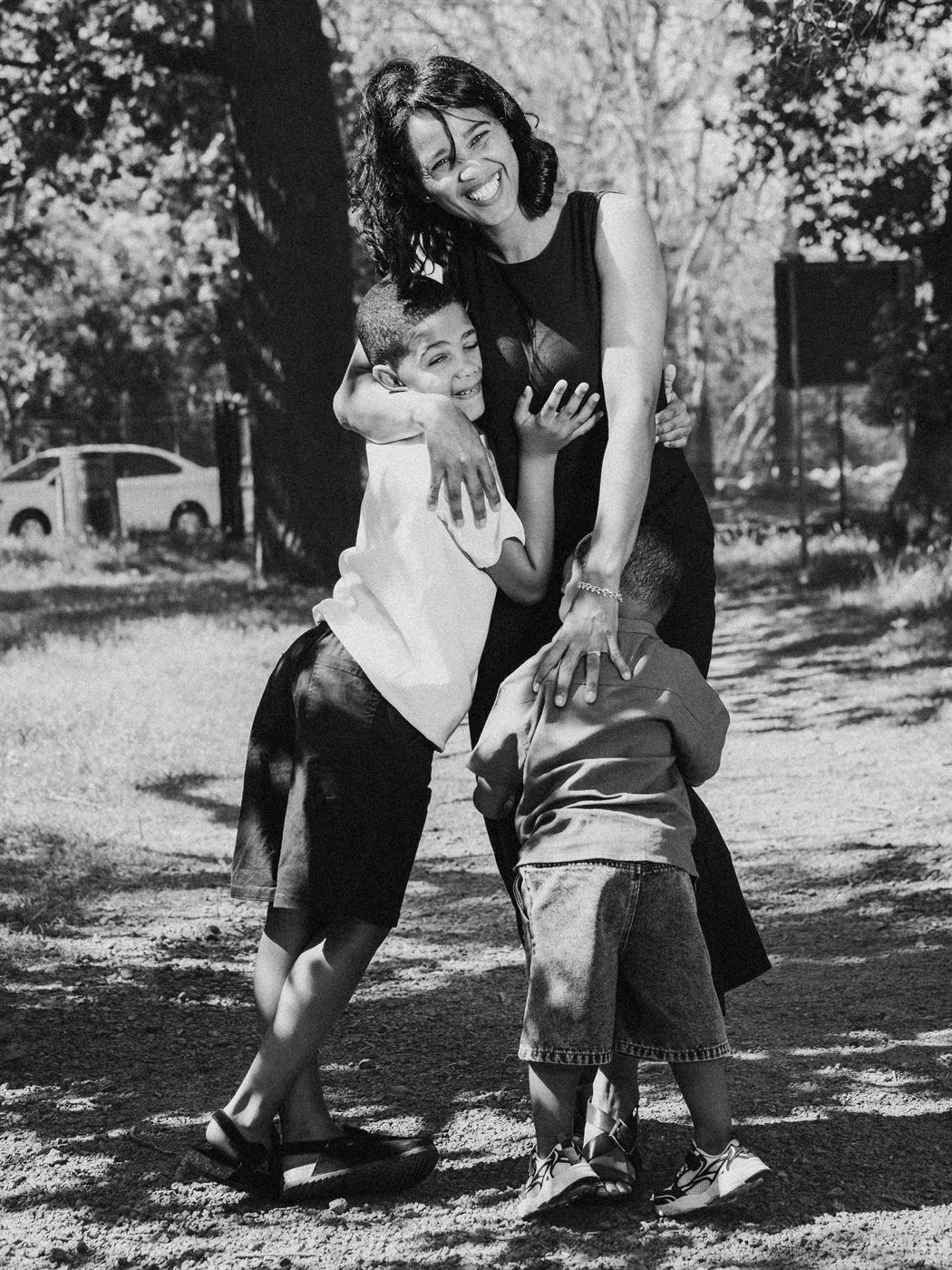 Black and white photograph of a mother holding her two sons close