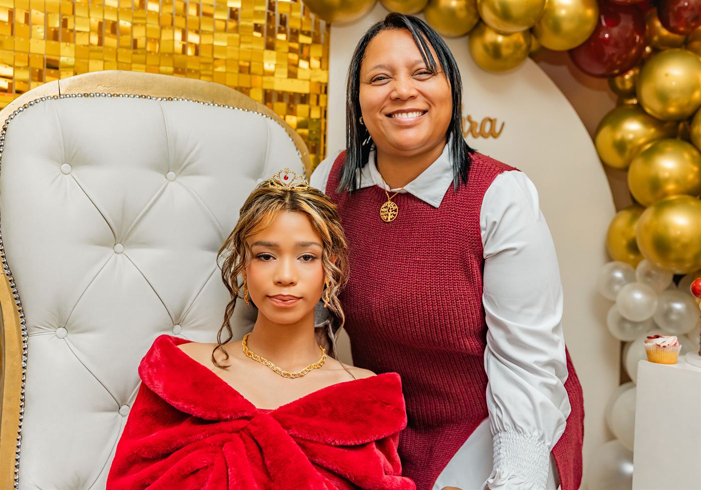 Young woman seated in a gold-backed chair with her mother beside her