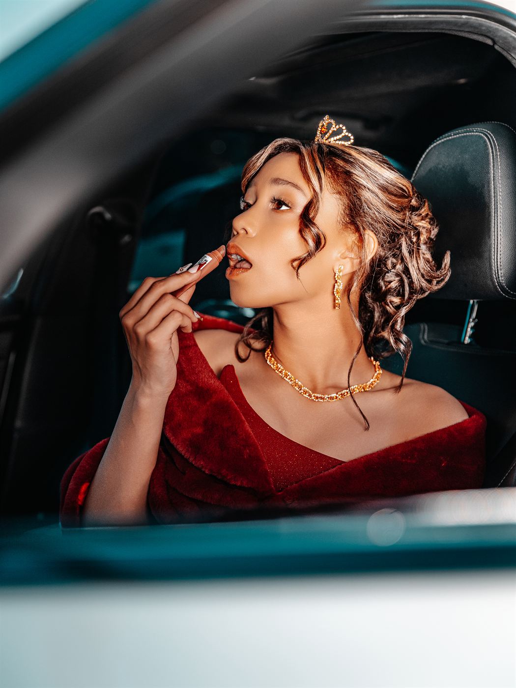 Young woman applying lipstick in a car before her matric farewell