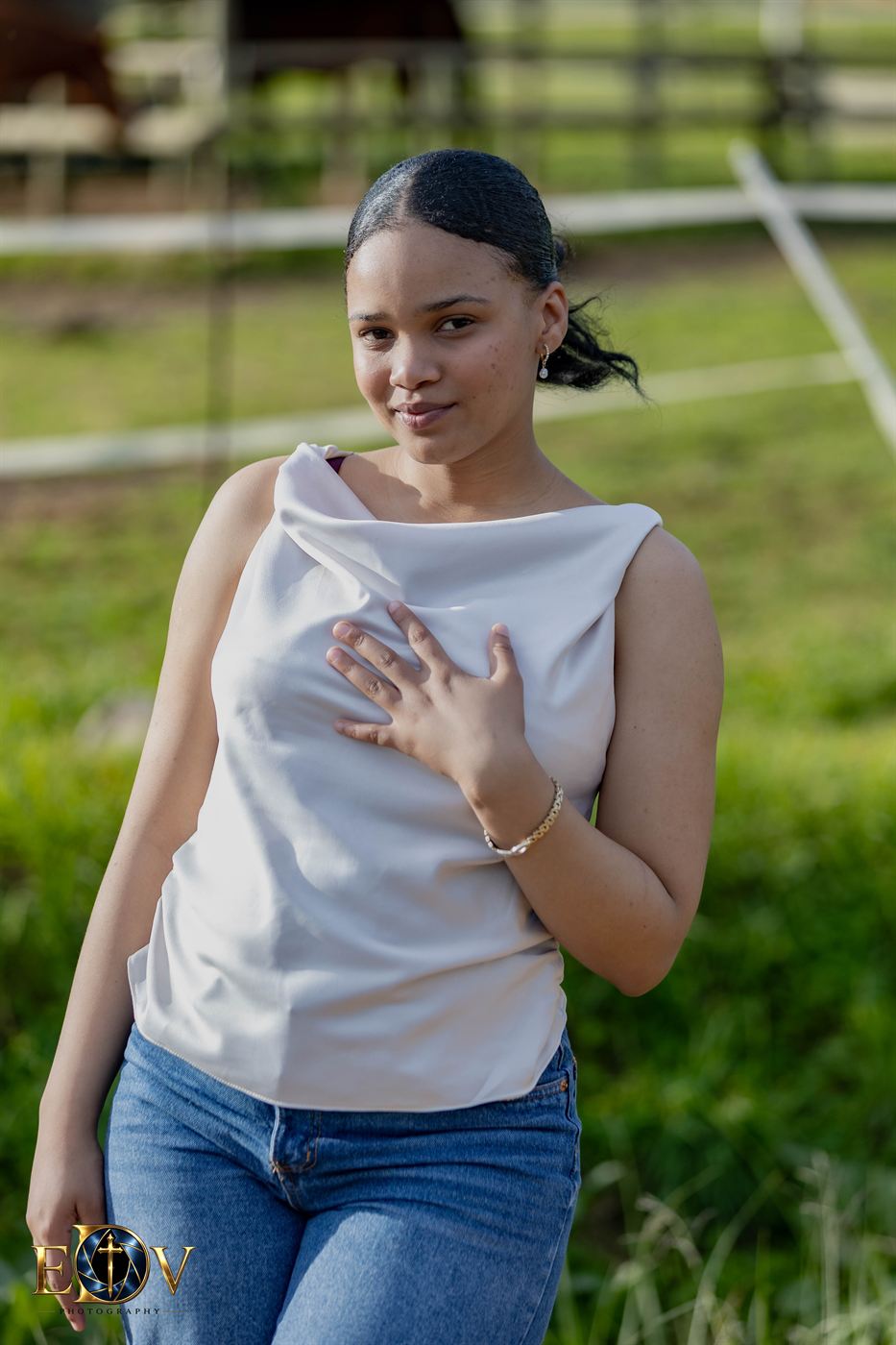 Portrait of a young woman in a satin top, hand resting on her chest