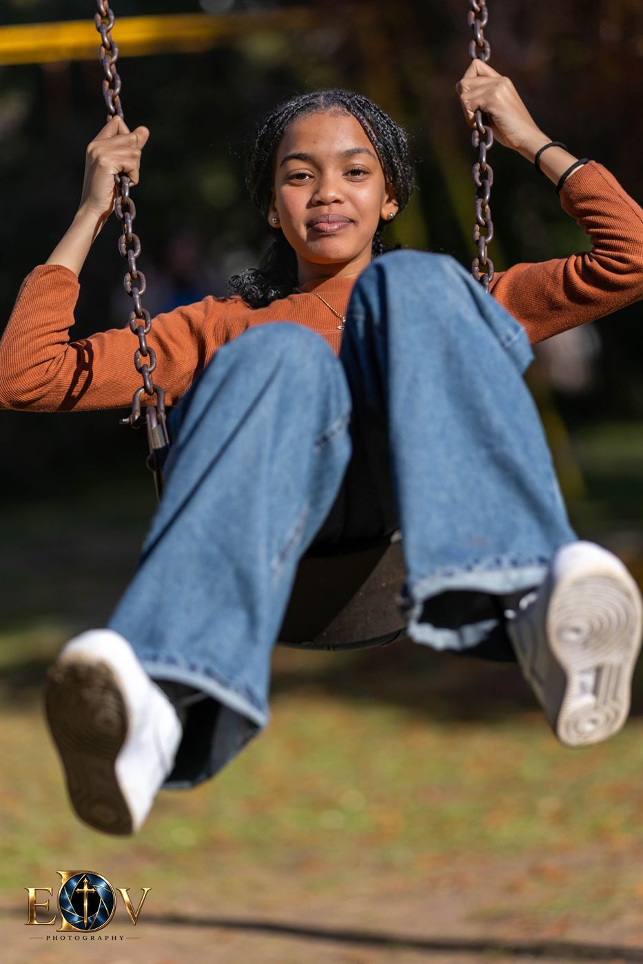 Celebratory portrait — young woman laughing mid-swing in a park