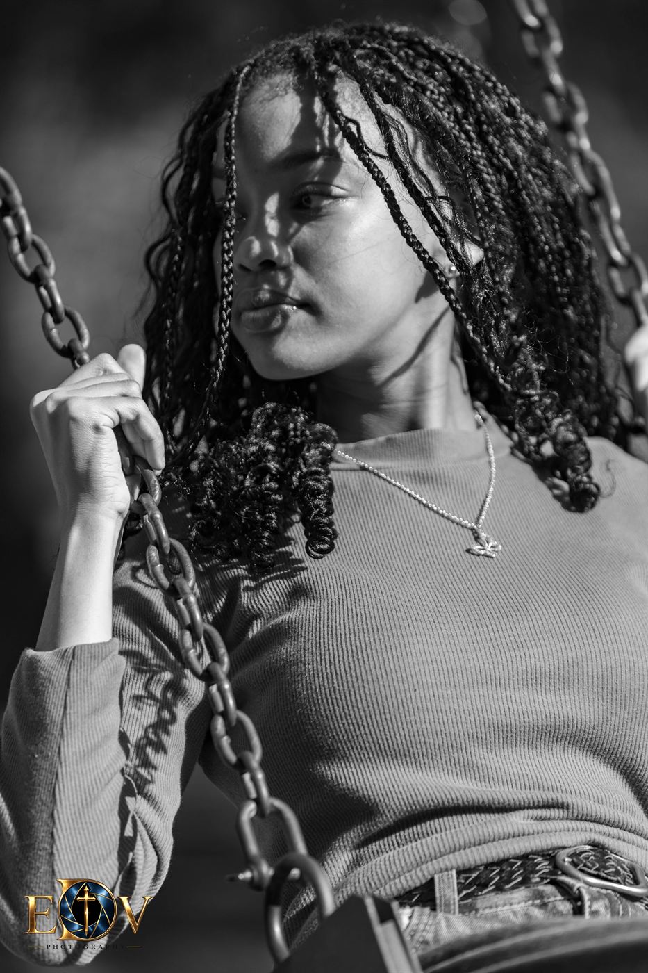 Black and white portrait of a young woman on a swing in hard sunlight